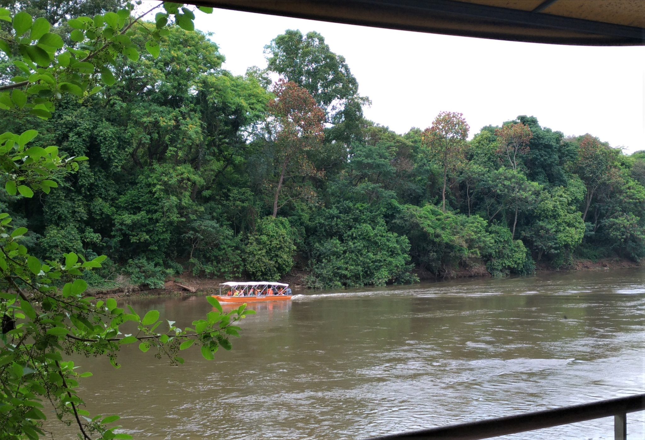 Rio, árvores e barco navegando com tripulantes